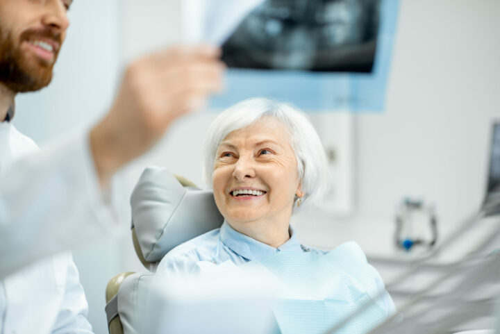 Smile in a Day™ - Dentist showing x-ray to the elder woman in the dentall office